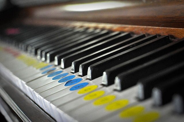 Close up of piano keys with colourful finger-guide stickers on the keys